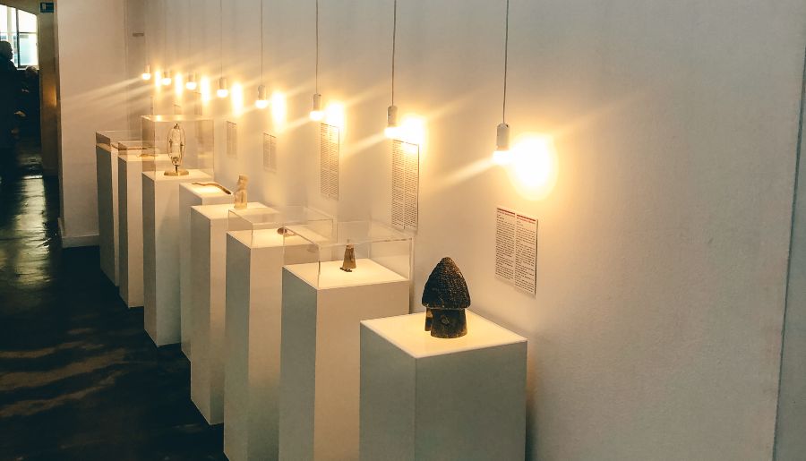Artifacts sitting on top of white columns under lights at the museum of broken relationships in Zagreb