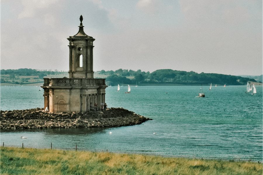A church in the middle of the lake with boats floating by