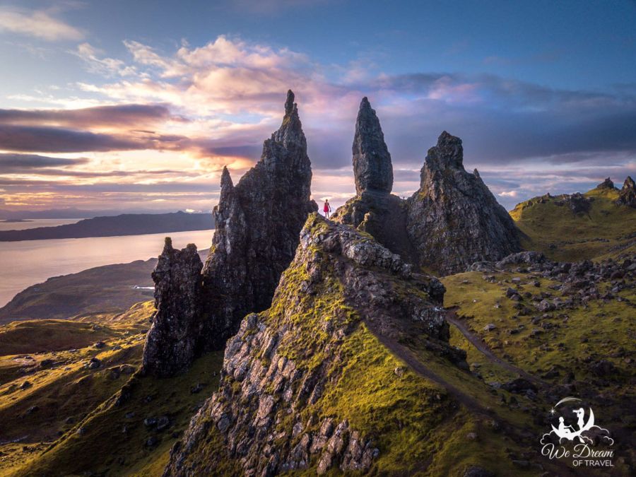 A girl in a red dress standing on the rocks at sunset at the Old Man of Storr on the Isle of Skye